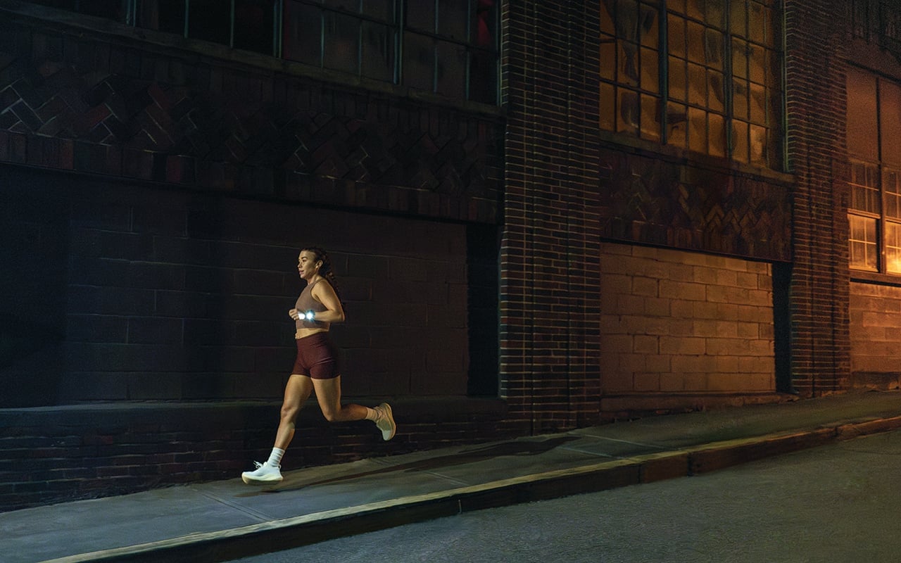 Woman running in the dark with her Garmin smartwatch flashlight on.