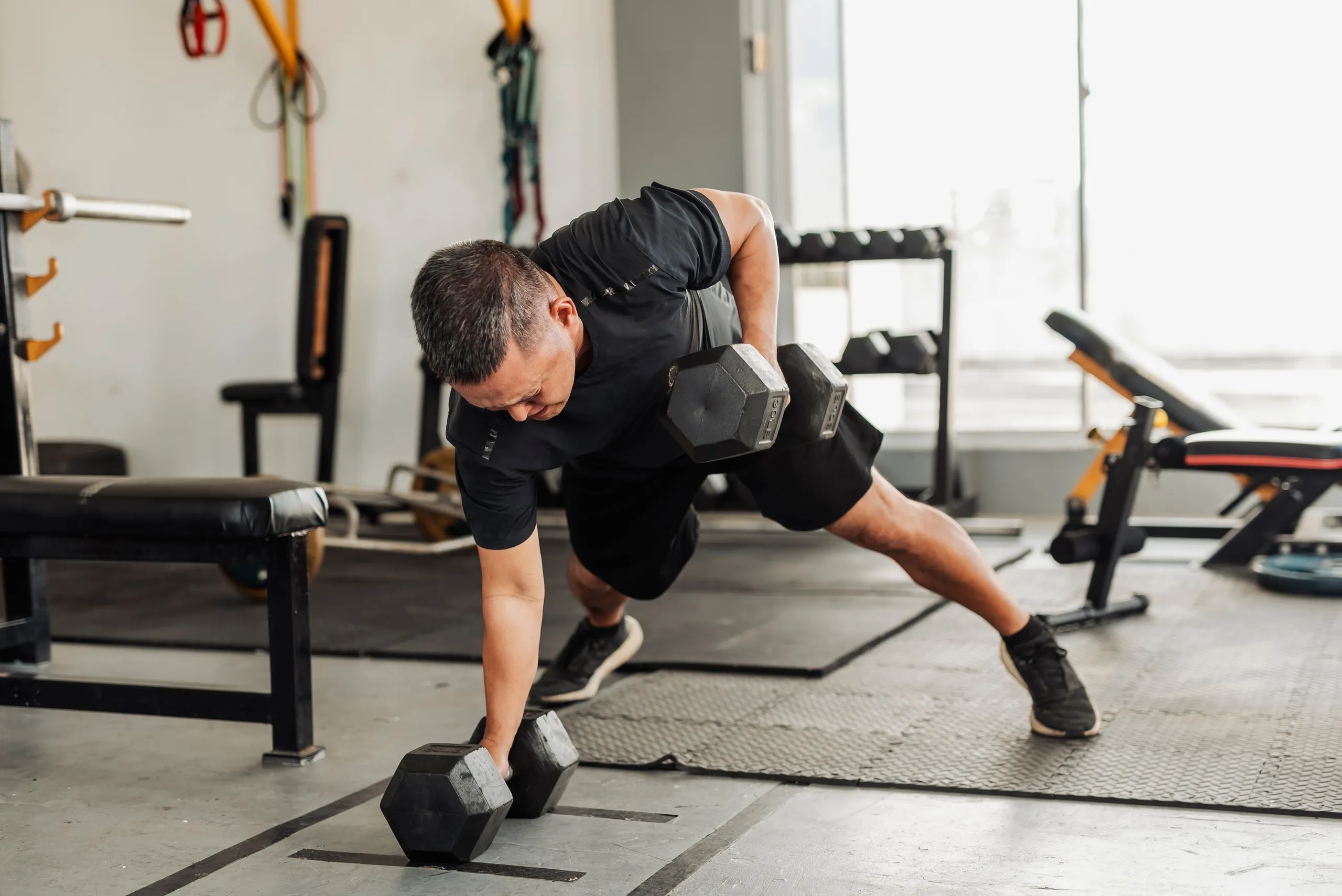 Strength Training with dumbbells: Men practicing the Renegade Row exercise in the gym